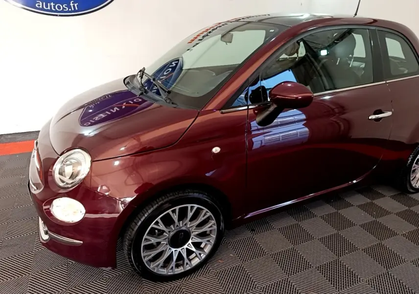 Vue 3/4 avant droit d'une FIAT 500 rouge brillant avec jantes alliage et rétroviseur assorti.
