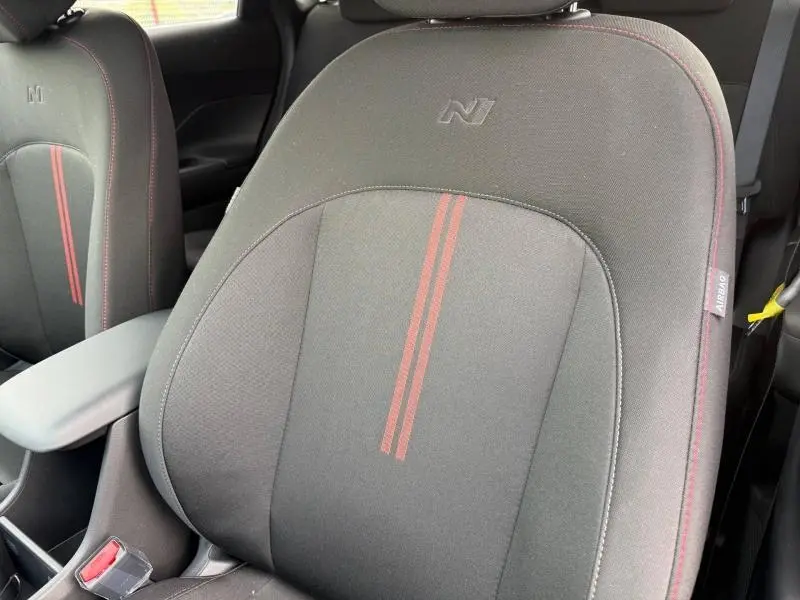 Gros plan sur les sièges avant noirs avec surpiqûres rouges et logo N du Hyundai Kona 2025 en intérieur.