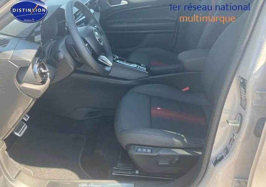 Vue intérieure côté conducteur d'une Alfa Romeo Junior 1.2 hybride ivoire et noir, siège électrique en cuir noir et tableau de bord moderne.