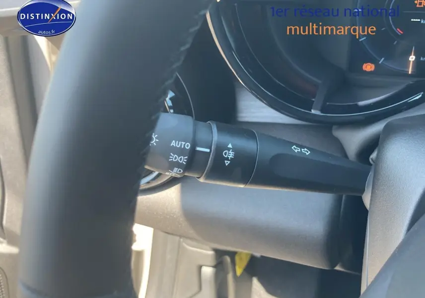 Gros plan sur la commande des feux et clignotants derrière le volant d’une Alfa Romeo Junior ivoire/noir.