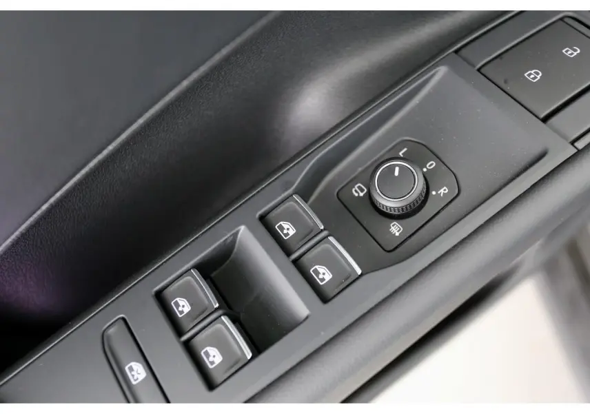 Gros plan sur les commandes de lève-vitres et réglage des rétroviseurs côté conducteur du Volkswagen T-Roc gris.