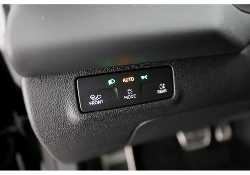 Gros plan sur le bouton de réglage automatique des feux dans un Volkswagen T-Roc gris Loup 2026.