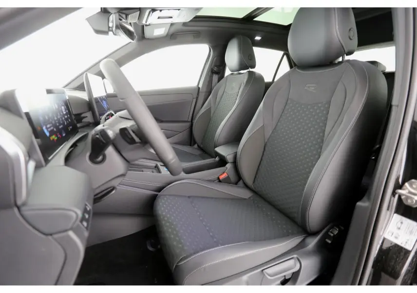 Vue intérieure côté conducteur du Volkswagen T-Roc 2026, sièges sport R-Line en tissu noir avec surpiqûres grises.