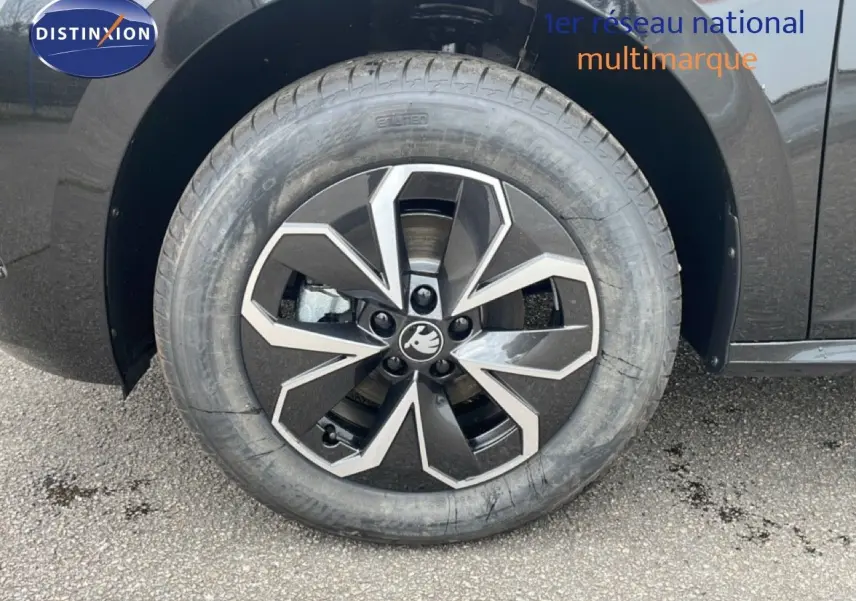 Gros plan sur la roue avant gauche d'un Skoda Kamiq noir magique métal avec jante alliage bicolore.