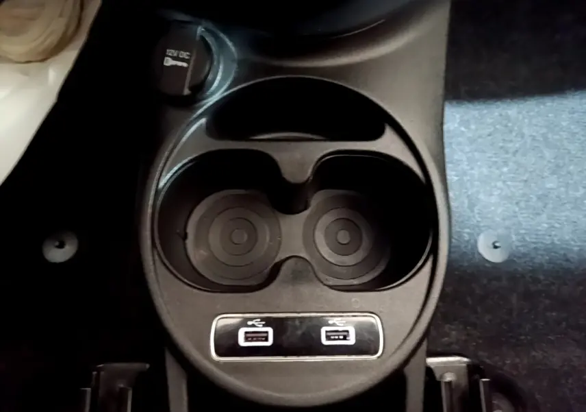 Gros plan sur le porte-gobelets central avec prises USB doubles dans l'habitacle d'une FIAT 500 gris foncé.