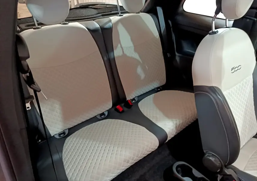 Vue intérieure sur les sièges arrière et avant beige matelassés de la FIAT 500 Hybrid gris foncé, version Dolcevita.