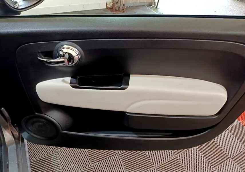 Gros plan sur la porte intérieure côté gauche de la FIAT 500 Dolcevita 2021 avec insert beige et poignée chromée.
