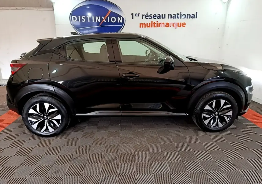 Vue de profil côté gauche d'un Nissan Juke noir 2023 avec jantes alliage bicolores et poignées de porte intégrées.