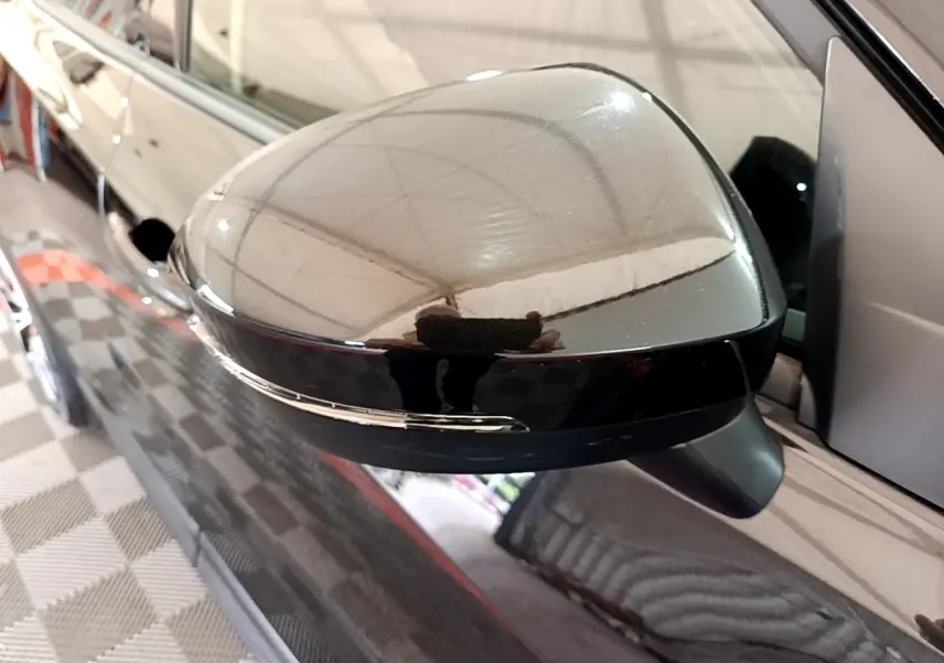 Rétroviseur extérieur noir côté conducteur du Nissan Juke 2023 avec clignotant intégré, vue rapprochée en intérieur.