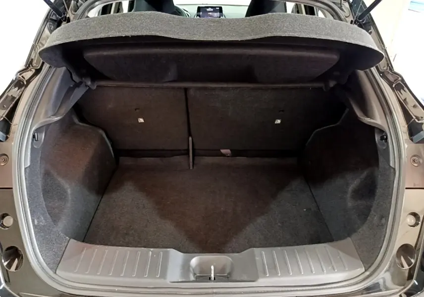 Coffre ouvert vu de l'arrière d'un Nissan Juke noir 2023, montrant l'espace de chargement et la tablette cache-bagages.