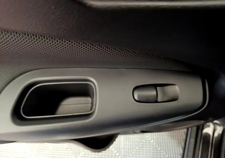 Gros plan sur la poignée intérieure de porte côté conducteur du Nissan Juke noir 2023, avec commande de verrouillage.