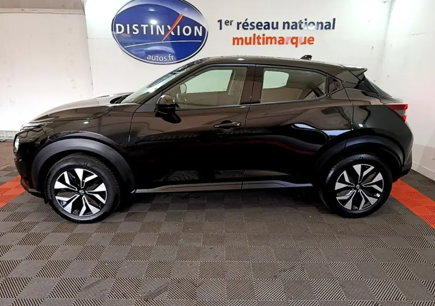Profil droit du Nissan Juke noir 2023 DIG-T 114 BVM6 Acenta, avec jantes alliage bicolores et poignées de porte ton caisse.