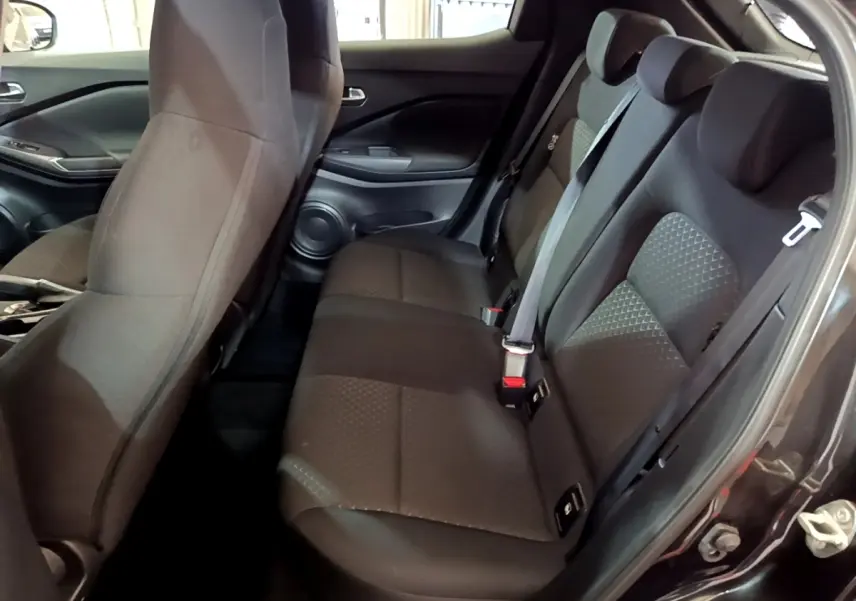 Vue intérieure côté droit montrant la banquette arrière noire du Nissan Juke 2023 avec ceintures et appuie-têtes intégrés.