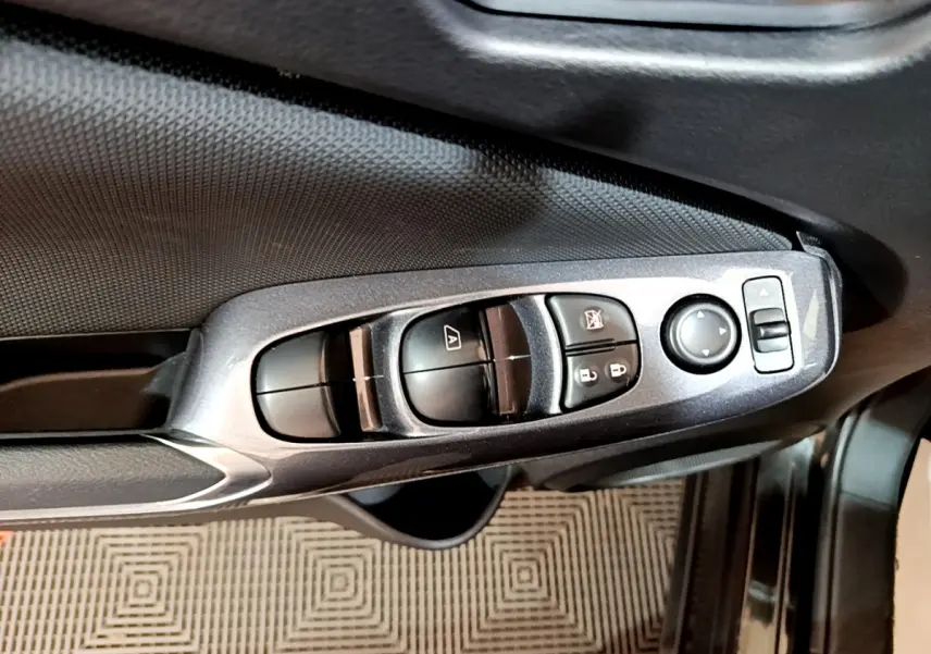 Gros plan sur les commandes de lève-vitres et rétroviseurs côté conducteur d’un Nissan Juke noir 2023.