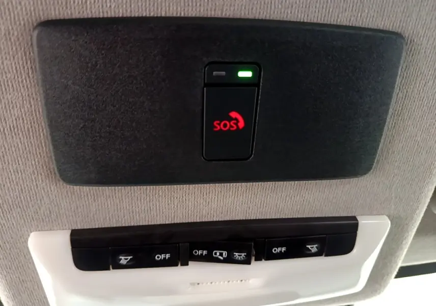 Bouton SOS rouge éclairé sur panneau de plafond gris clair dans l'habitacle du Nissan Juke noir 2023.