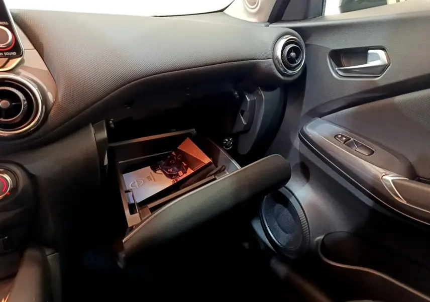 Intérieur côté passager du Nissan Juke noir 2023, avec boîte à gants ouverte et tableau de bord texturé.