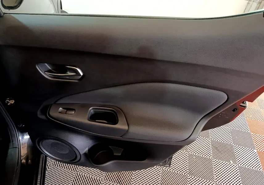 Gros plan sur la porte côté gauche noire du Nissan Juke 2023, avec poignée intégrée et haut-parleur rond visible.