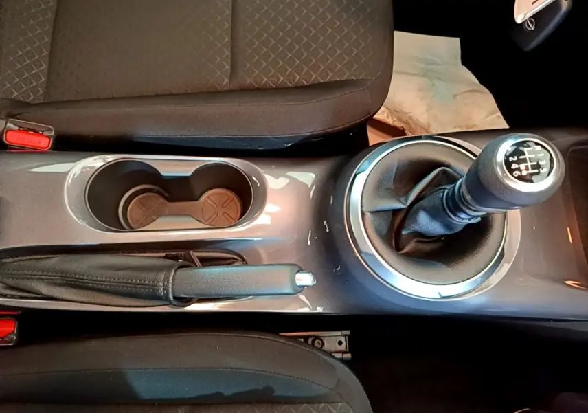 Vue plongeante sur la console centrale du Nissan Juke noir 2023, avec levier de vitesse manuel et frein à main.