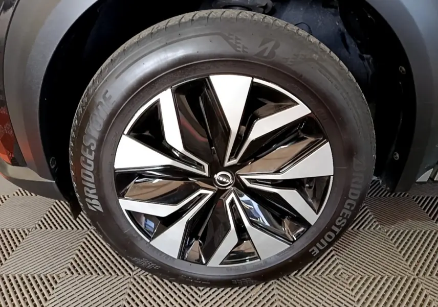 Gros plan sur la jante noire et argentée du Nissan Juke 2023 avec pneu Bridgestone, partie avant droite visible.