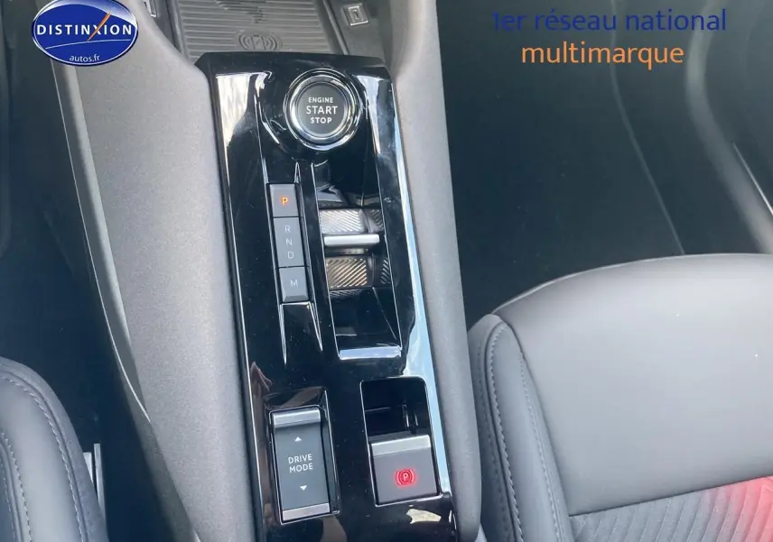 Vue rapprochée de la console centrale noire de l'Alfa Romeo Junior 1.2 hybride 2026 avec bouton start/stop et commande boîte auto.