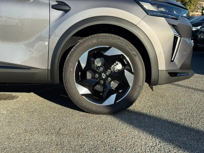 Gros plan sur la roue avant droite d’un Renault Captur gris avec jante alliage noire et argentée au design géométrique.