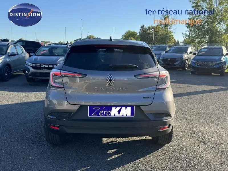 Vue arrière d'un Renault Captur gris avec feux arrière LED, stationné en extérieur parmi d'autres véhicules.