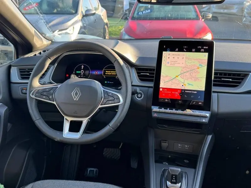 Vue intérieure du tableau de bord du Renault Captur 2025 avec volant multifonction et écran tactile vertical affichant la navigation.