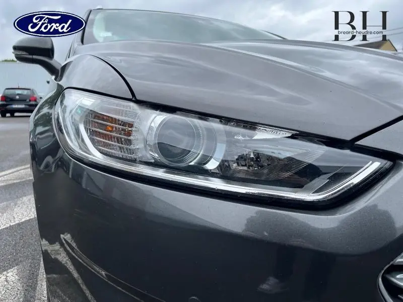 Gros plan sur le phare avant gauche d'une Ford Mondeo SW gris Magnetic, soulignant son design moderne et précis.