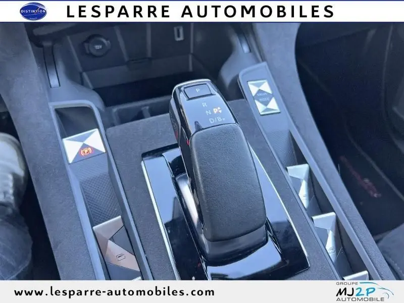 Gros plan sur la console centrale du DS7 Crossback gris, mettant en valeur le levier de vitesses automatique et les commandes environnantes.