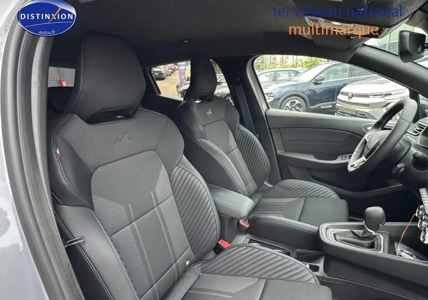 Intérieur avant de la Renault Clio V gris rafale, sièges sport esprit Alpine avec surpiqûres bleues et accoudoir central.