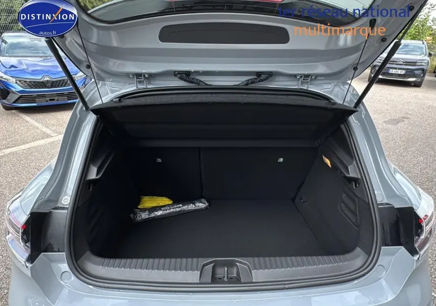 Coffre ouvert vu de l'arrière d'une Renault Clio V gris rafale, avec intérieur noir et accessoires rangés.