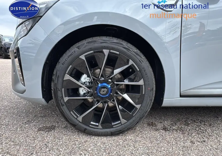 Gros plan sur la roue avant gauche de la Renault Clio V gris rafale avec jante alu 17 esprit alpine noire et bleue.