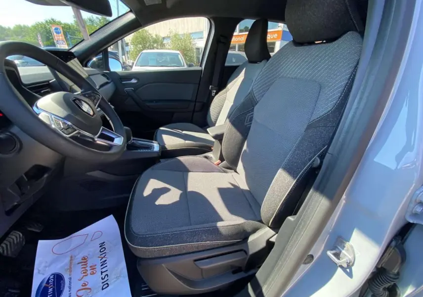 Vue intérieure côté conducteur du Renault Captur 2025 avec sièges tissu gris et volant multifonction noir.