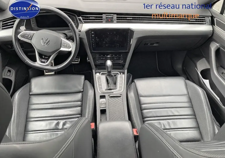 Vue intérieure avant de la Volkswagen Passat SW 2.0 TDI R-Line 2021 avec sièges cuir noirs et console centrale moderne.