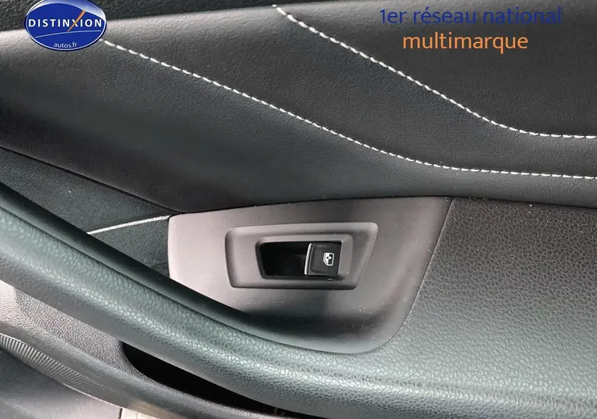 Bouton de commande de vitre sur la porte côté gauche d'une Volkswagen Passat SW noire, intérieur cuir noir avec surpiqûres blanches.