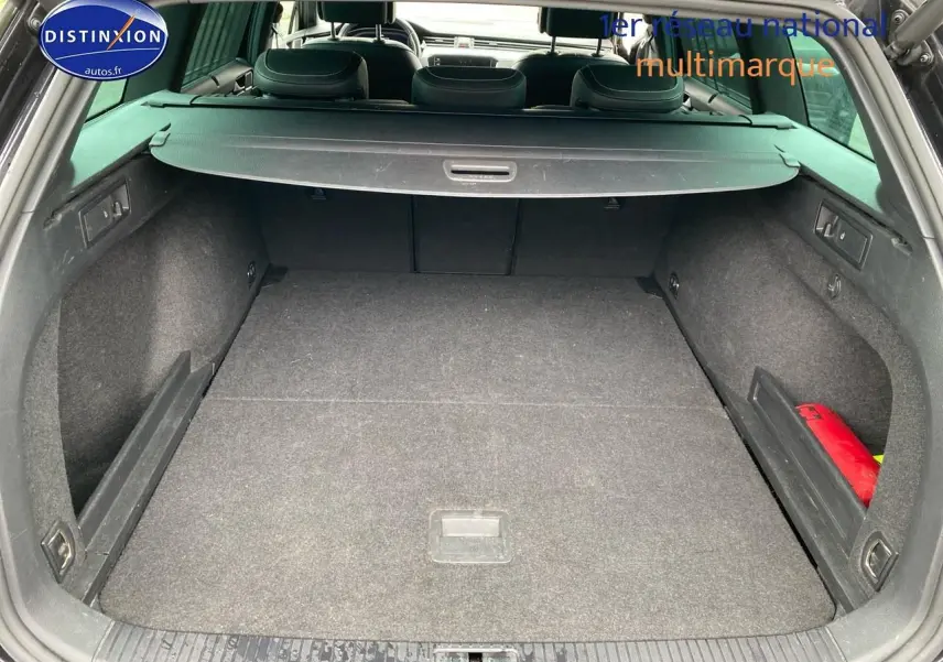 Coffre ouvert vu de l'arrière d'une Volkswagen Passat SW noire avec cache-bagages et intérieur sombre.
