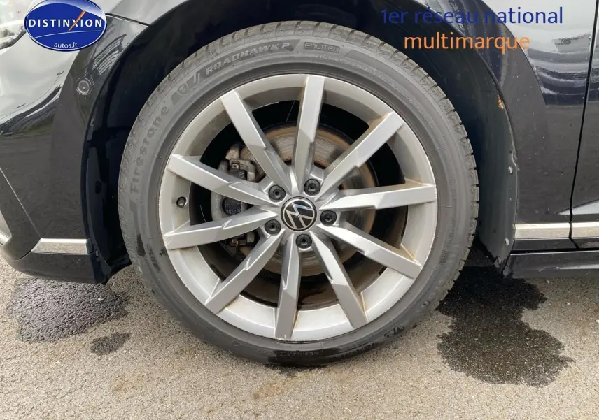 Gros plan sur la jante alu argentée et pneu Firestone d'une Volkswagen Passat SW noire côté avant droit.