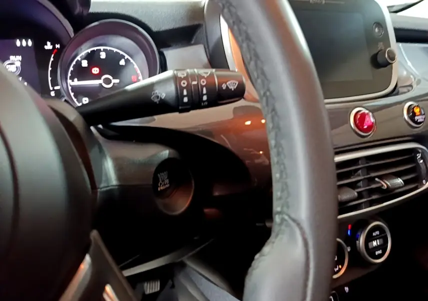 Vue intérieure rapprochée du tableau de bord et volant du Fiat 500X gris foncé, avec écran tactile et commandes visibles.