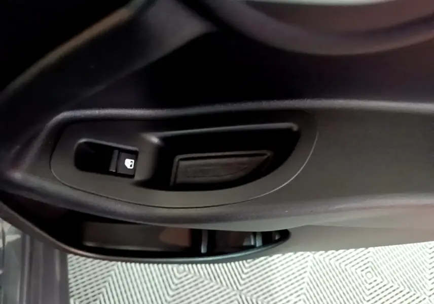 Gros plan sur la poignée intérieure et le bouton de verrouillage de la porte côté conducteur d'une FIAT 500X gris foncé.