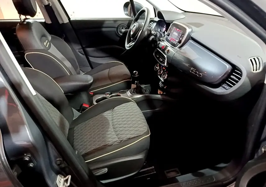 Vue intérieure côté conducteur du Fiat 500X gris foncé, mettant en valeur les sièges noirs et le tableau de bord avec écran tactile.