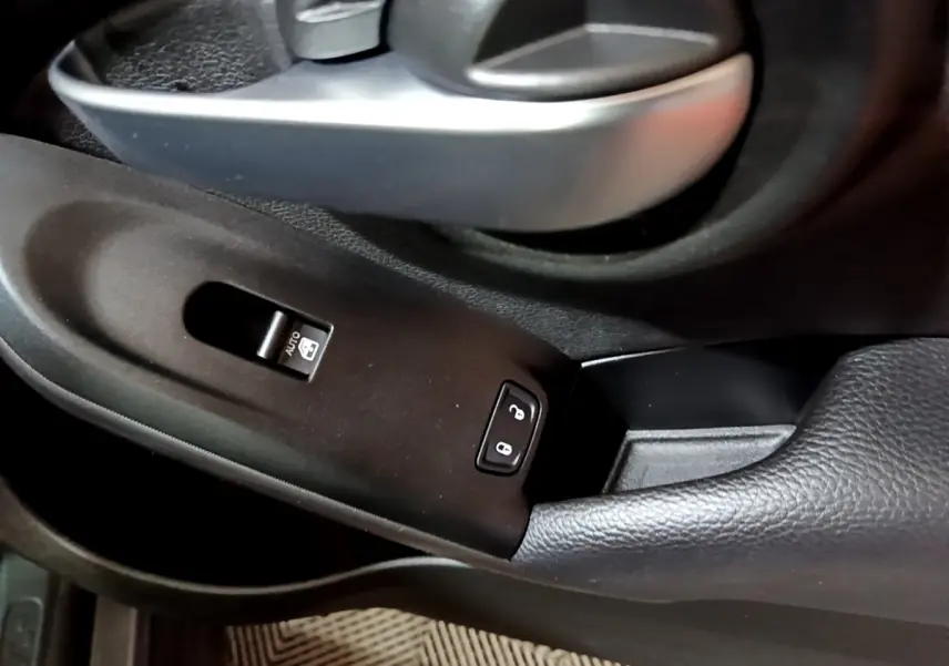 Gros plan sur la poignée de porte intérieure et les commandes de verrouillage de la FIAT 500X gris foncé côté conducteur.