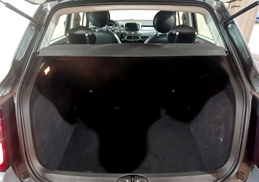 Coffre ouvert d'une FIAT 500X gris foncé vue arrière, montrant l'habitacle et la tablette cache-bagages.