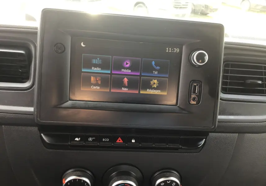 Écran tactile central du tableau de bord du Renault Master blanc, avec commandes climatisation et boutons fonctionnels visibles.