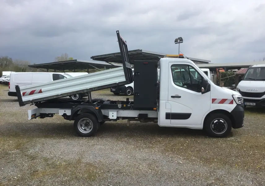 Vue latérale droite d’un Renault Master blanc 2023 avec benne relevée et coffre noir, roues jumelées visibles.
