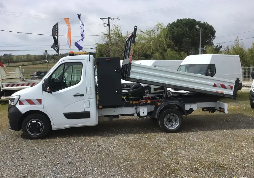 Renault Master benne blanche vue de profil côté gauche, benne relevée avec coffre noir fixé derrière la cabine.