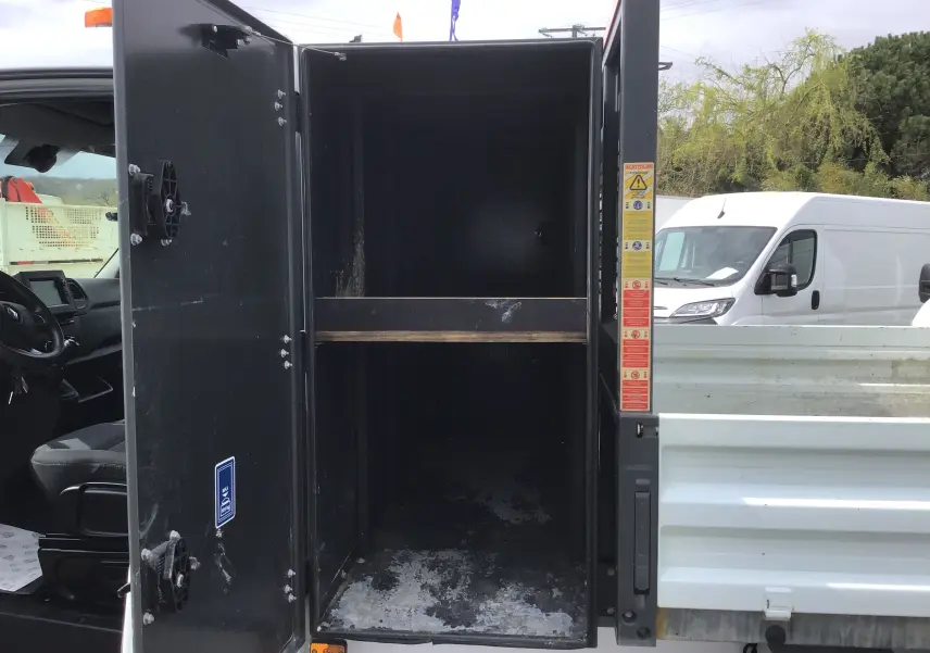 Vue latérale gauche d'un Renault Master blanc 2023 avec benne et coffre ouvert montrant l'intérieur noir du coffre.