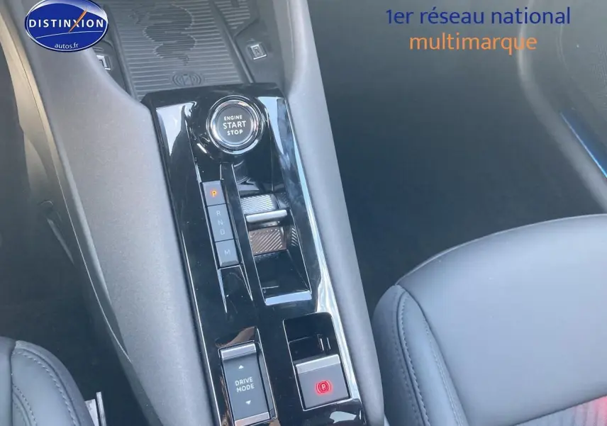Gros plan sur la console centrale noire brillante de l'Alfa Romeo Junior 1.2 hybride avec bouton start/stop et commandes de boîte auto.