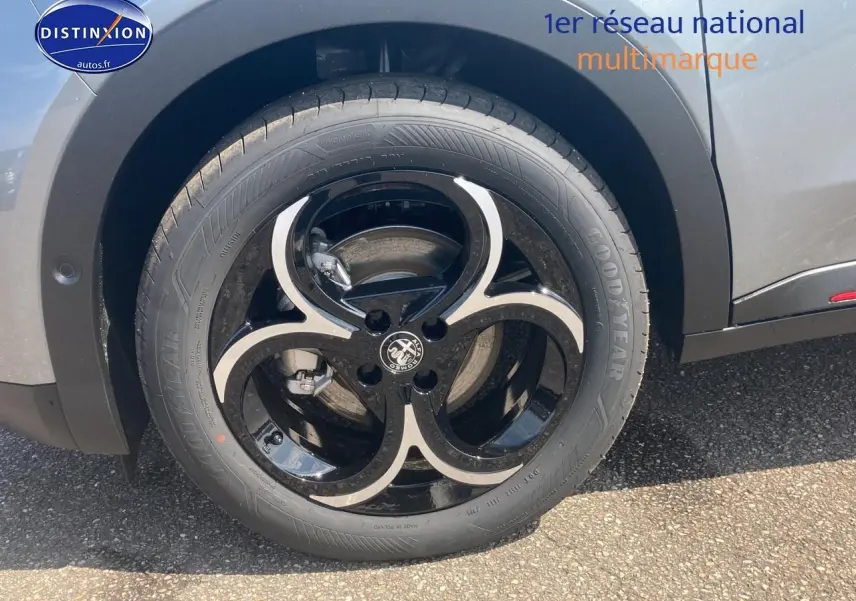 Gros plan sur la roue avant droite de l'Alfa Romeo Junior 1.2 hybride gris t/noir avec jante alliage noire et argent.