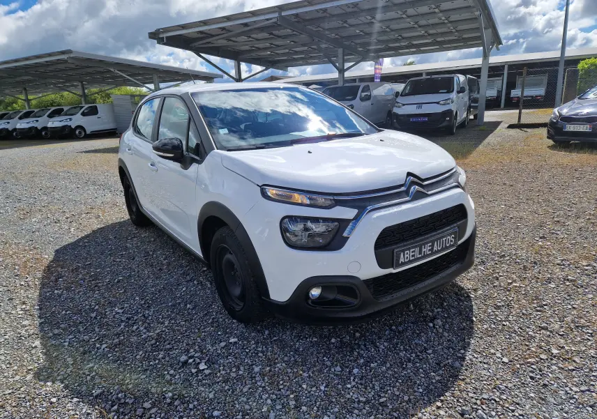 Citroën C3 Société blanc vue 3/4 avant droit, avec calandre noire et feux LED distinctifs, sur parking extérieur.