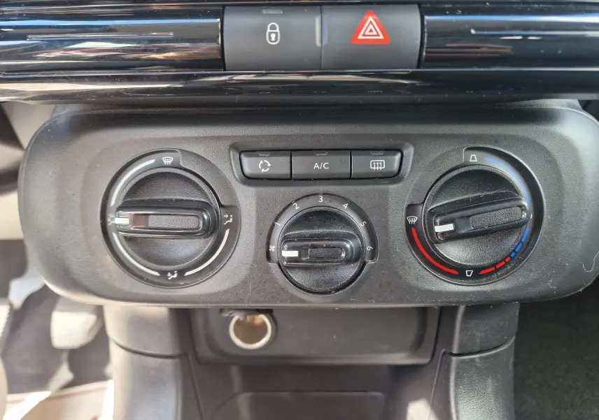 Vue rapprochée du tableau de bord de la Citroën C3 Société blanc, montrant les commandes de climatisation et ventilation.